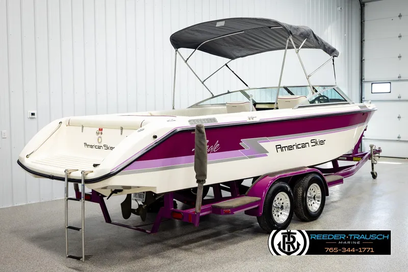 Slide: The Image of 1993 American Skier Eagle boat with purple accents on a trailer in a showroom. - 5
