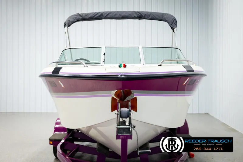 Slide: The Image of 1993 American Skier Eagle boat with purple accents on a trailer in a showroom. - 7