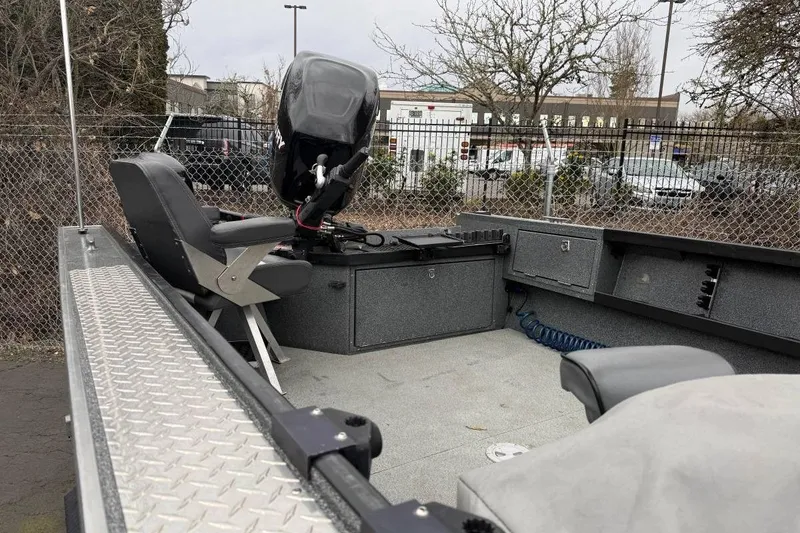 Slide: The Image of 2012 Alumaweld Super Vee Pro 23 boat interior with seating and motor, parked outdoors. - 3