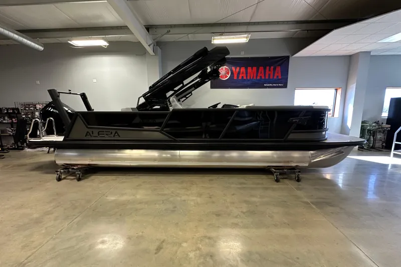 The Image of 2026 Alera M25L pontoon boat displayed indoors with Yamaha banner. - 1