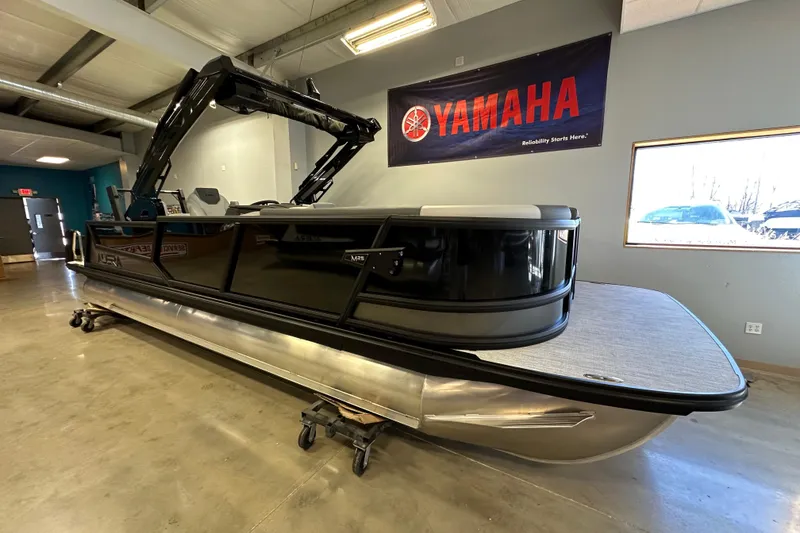 Slide: The Image of 2026 Alera M25L pontoon boat displayed indoors with Yamaha banner. - 2