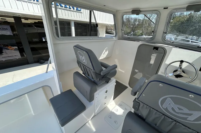 Slide: The Image of Interior of 2026 May-Craft 245 Pilot House boat with seating and steering wheel. - 10