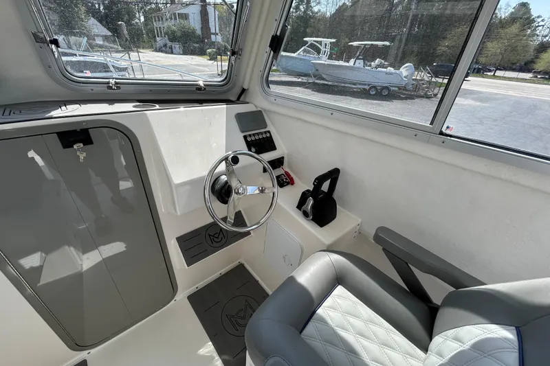 Slide: The Image of Interior of 2026 May-Craft 245 Pilot House boat with steering wheel and seating. - 11
