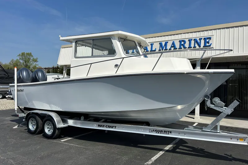 Slide: The Image of 2026 May-Craft 245 Pilot House boat on trailer outside a marine dealership. - 2