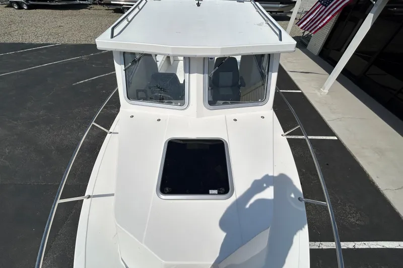 Slide: The Image of 2026 May-Craft 245 Pilot House boat, top view, in a parking lot with American flag. - 26