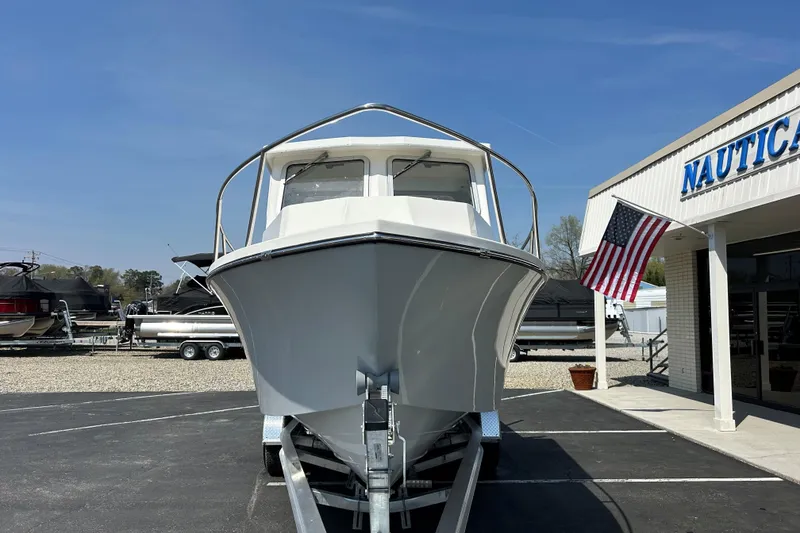 Slide: The Image of 2026 May-Craft 245 Pilot House boat displayed outside a nautical store with American flag. - 3