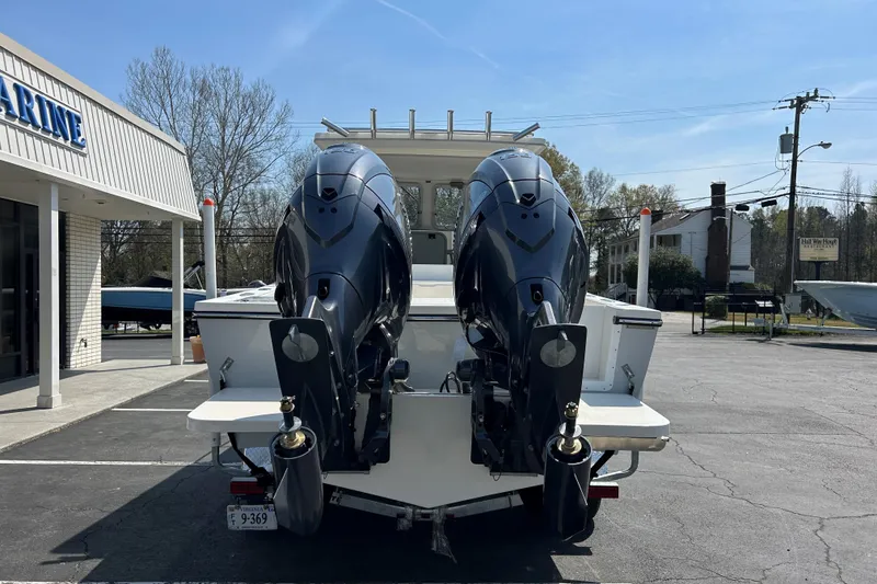 Slide: The Image of 2026 May-Craft 245 Pilot House boat with dual outboard motors in a marina parking lot. - 6