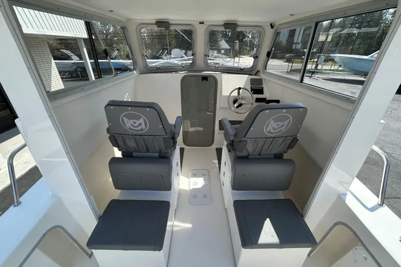 Slide: The Image of Interior of 2026 May-Craft 245 Pilot House boat, featuring dual seats and steering console. - 8
