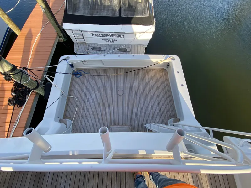 Slide: The Image of 1995 Mares 58 Power Cat boat docked, featuring spacious deck and fishing rod holders. - 15