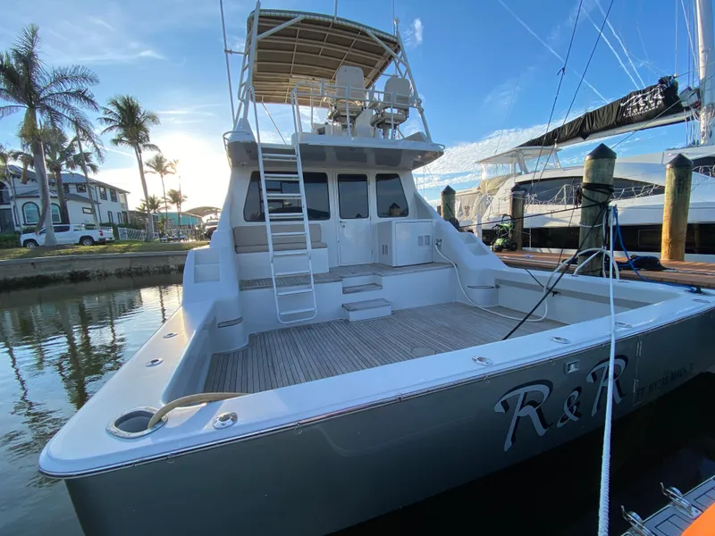 Slide: The Image of 1995 Mares 58 Power Cat docked, featuring spacious deck and ladder, with palm trees in background. - 23