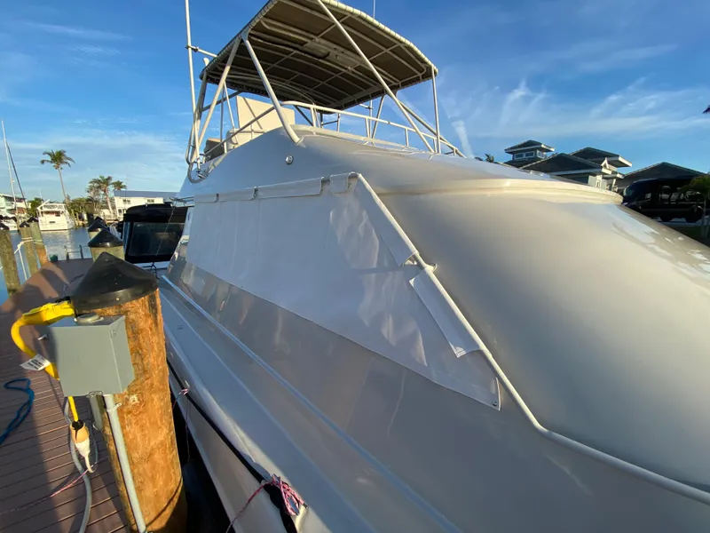 Slide: The Image of 1995 Mares 58 Power Cat docked, featuring sleek white exterior and covered upper deck. - 26