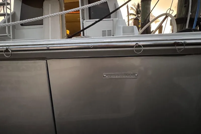 Slide: The Image of Side view of a 1995 Mares 58 Power Catamaran docked, showing sleek metallic finish. - 30