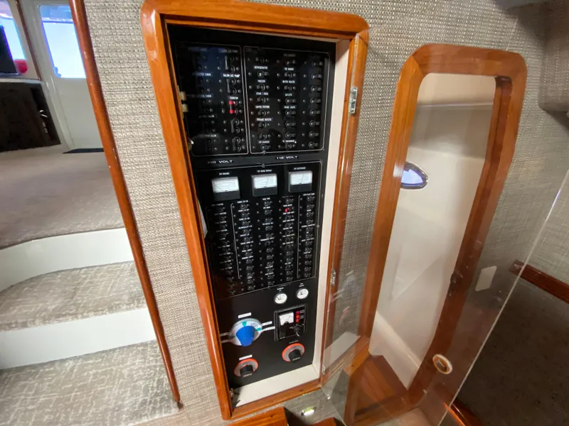 Slide: The Image of Electrical panel inside a 1995 Mares 58 Power Cat, featuring wood trim and carpeted stairs. - 48