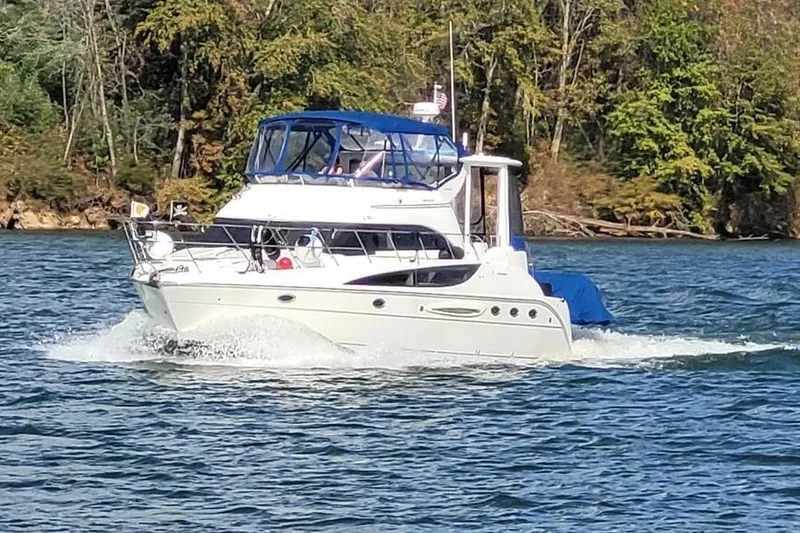 Slide: The Image of 2004 Meridian 459 Motoryacht cruising on a scenic lake with lush forest backdrop. - 2