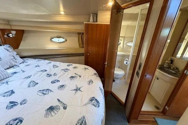 Slide: The Image of Luxurious 2004 Meridian 459 Motoryacht bedroom with ensuite bathroom and nautical-themed bedding. - 22