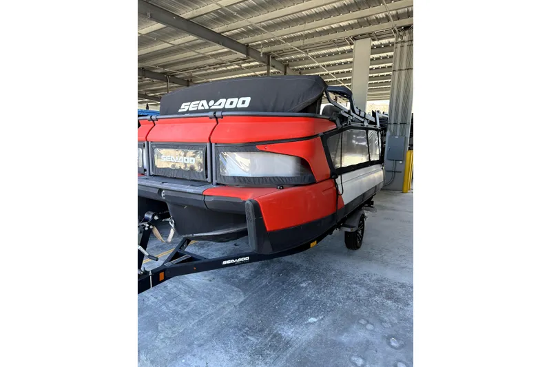 Slide: The Image of 2022 Sea-Doo Switch Cruise 18, red and black, parked under a metal roof. - 1