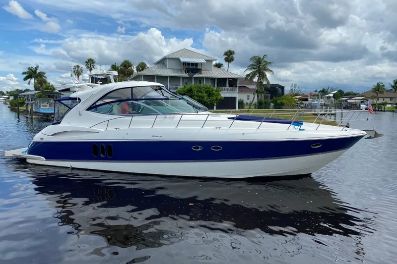 The Image of 2006 Cruisers Yachts 520 Express on calm water, with a scenic waterfront backdrop. - 0