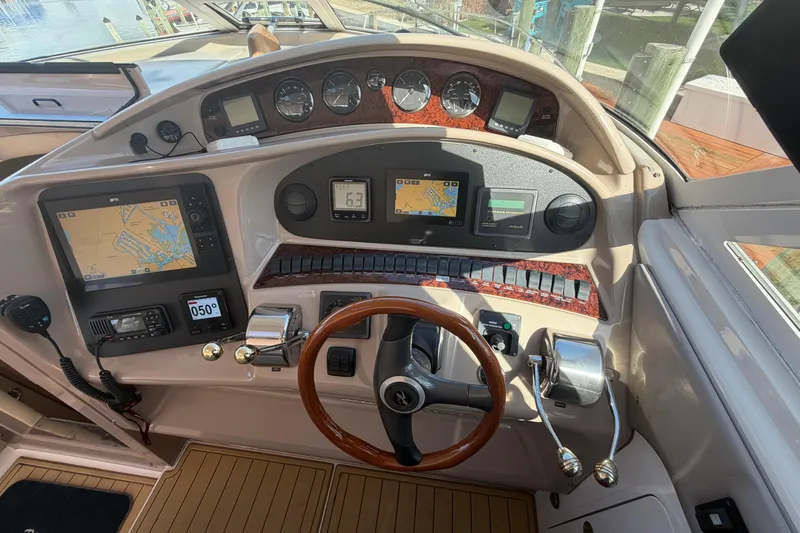 Slide: The Image of 2002 Sea Ray 480 Motor Yacht helm with navigation screens and wooden steering wheel. - 15