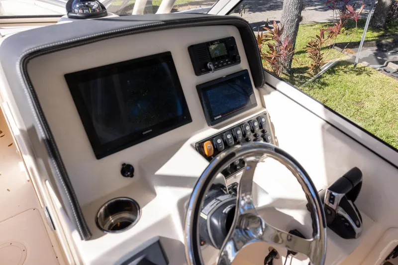 Slide: The Image of 2022 Grady-White Freedom 275 boat dashboard with steering wheel and electronic controls. - 13