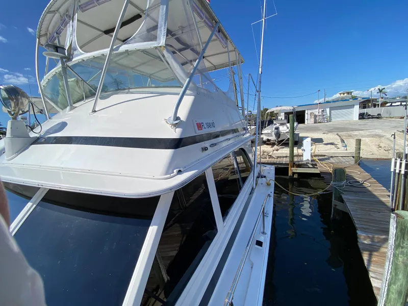 Slide: The Image of 1982 Bertram 46.6 War Wagon docked, showcasing sleek design and spacious flybridge. - 10