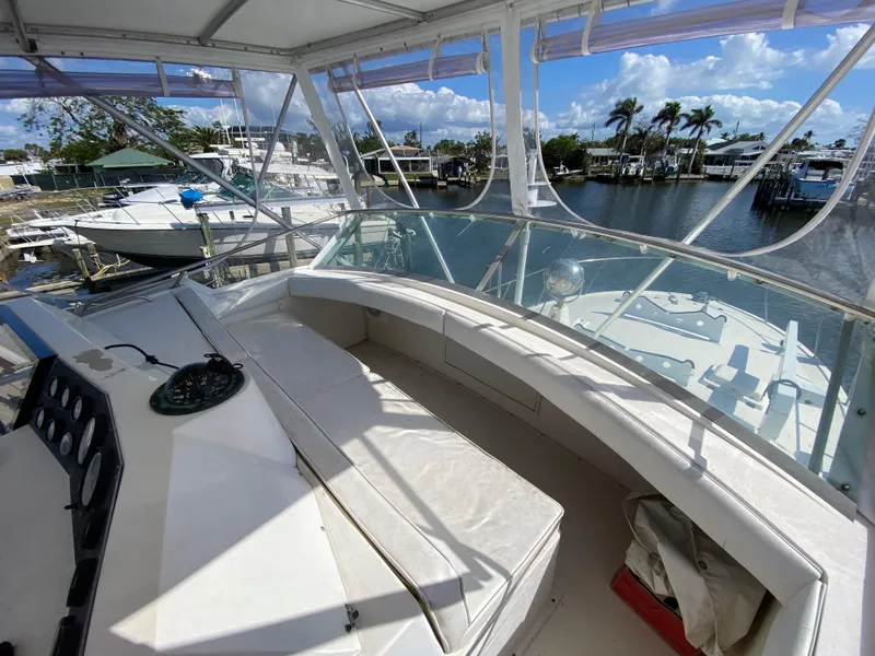 Slide: The Image of 1982 Bertram 46.6 War Wagon boat interior with seating, docked near palm trees and water. - 18