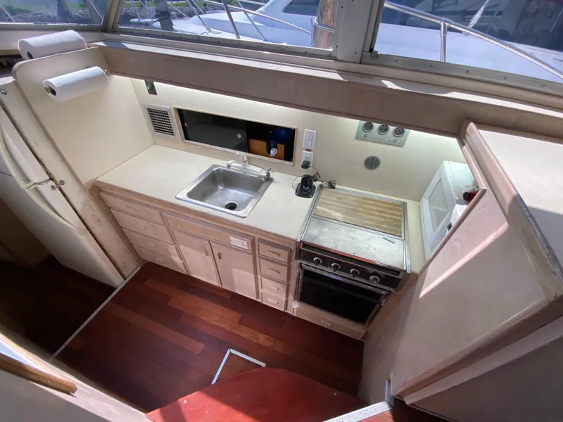 Slide: The Image of 1982 Bertram 46.6 War Wagon yacht kitchen with sink, stove, and wooden flooring. - 24