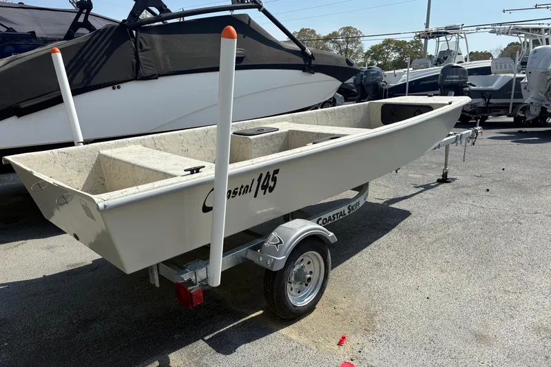 Slide: The Image of 2025 Coastal Skiff 145 boat on trailer, parked outdoors in a marina. - 1