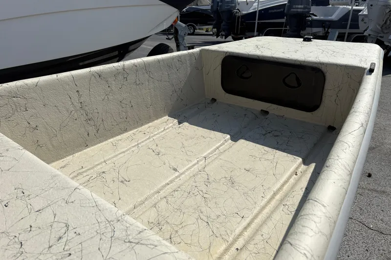 Slide: The Image of 2025 Coastal Skiff 145 boat interior with textured flooring, parked outdoors. - 4
