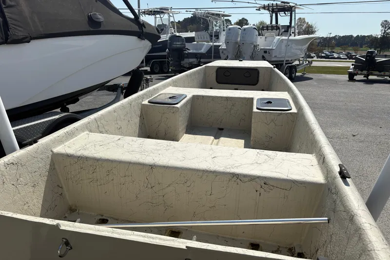 Slide: The Image of 2025 Coastal Skiff 145 boat interior with storage compartments, parked outdoors. - 7