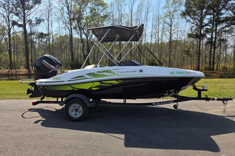 The Image of 2022 Tahoe T16 boat on trailer, parked outdoors with trees in background. - 0