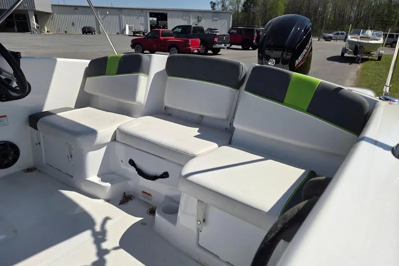 Slide: The Image of 2022 Tahoe T16 boat interior with white and green seating, parked outdoors. - 9