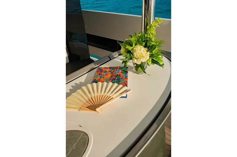 Slide: The Image of An elegant table on a yacht with a fan, a notebook, and a floral arrangement. - 20