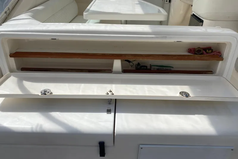 Slide: The Image of Open storage compartment on 2000 Riviera 4000 boat with wooden shelves and items. - 17