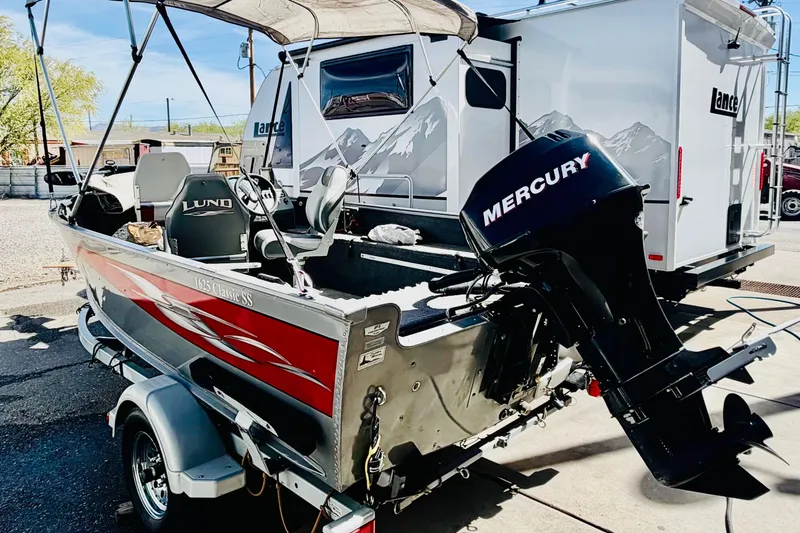 Slide: The Image of 2006 Lund 1625 Classic SS boat with Mercury outboard motor, parked near a camper. - 3