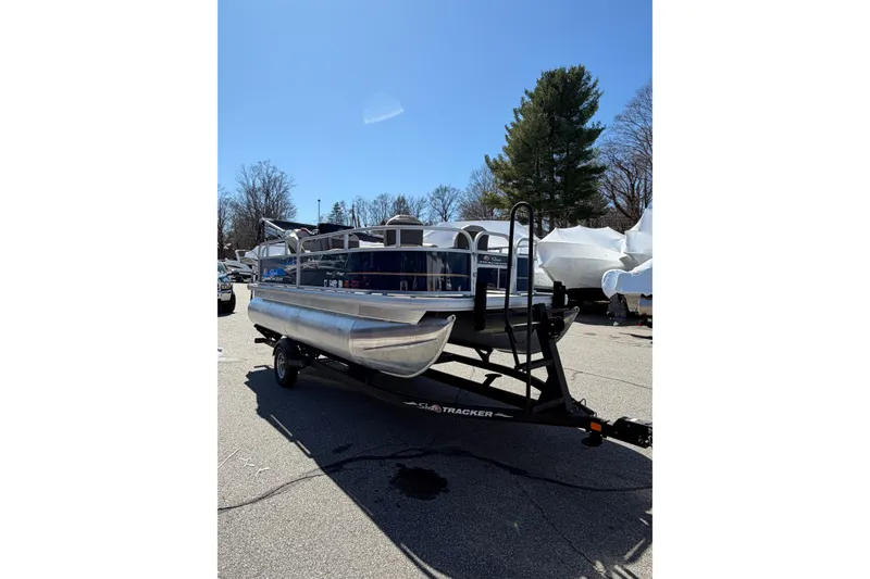 The Image of 2022 Sun Tracker Bass Buggy 16 XL pontoon boat on trailer under clear blue sky. - 0