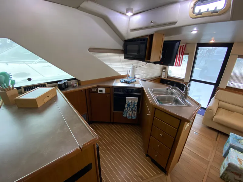 Slide: The Image of Interior of 2001 Bayliner 3988 yacht, featuring a modern kitchen with wood cabinetry. - 14