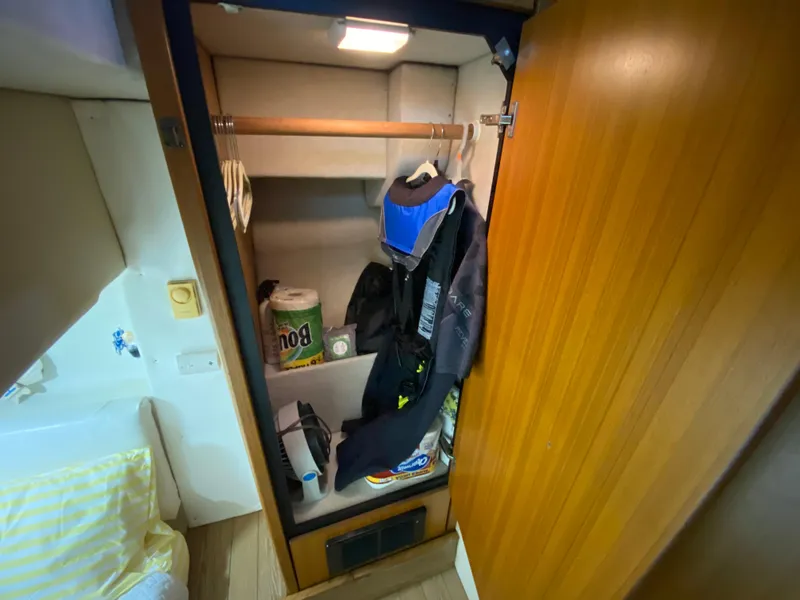Slide: The Image of Closet interior on a 2001 Bayliner 3988 boat, featuring clothes and household items. - 22