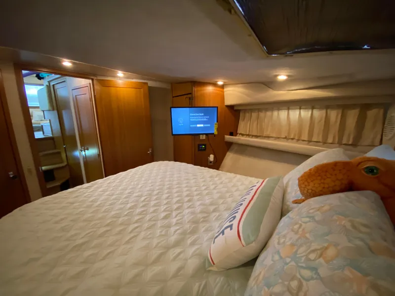 Slide: The Image of 2001 Bayliner 3988 yacht bedroom with cozy bedding, TV, and wooden cabinetry. - 29