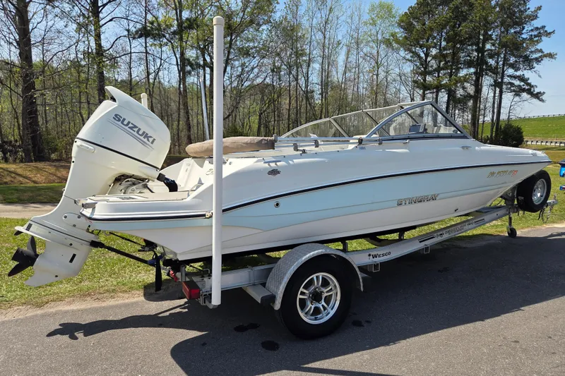 Slide: The Image of 2017 Stingray 191 DC boat on trailer with Suzuki outboard motor, parked outdoors. - 2