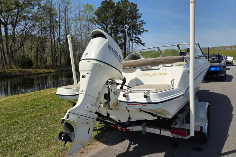 Slide: The Image of 2017 Stingray 191 DC boat with Suzuki outboard motor on a trailer by a scenic lake. - 3