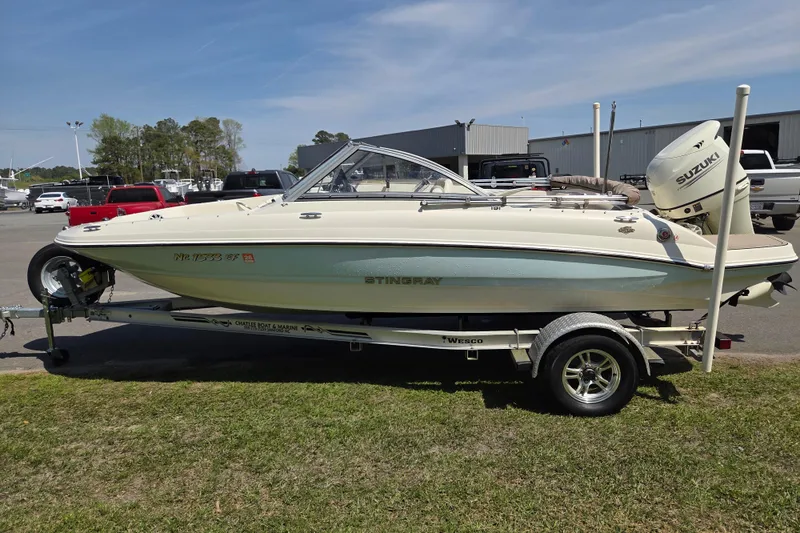 Slide: The Image of 2017 Stingray 191 DC boat on trailer, parked outdoors with Suzuki outboard motor. - 6