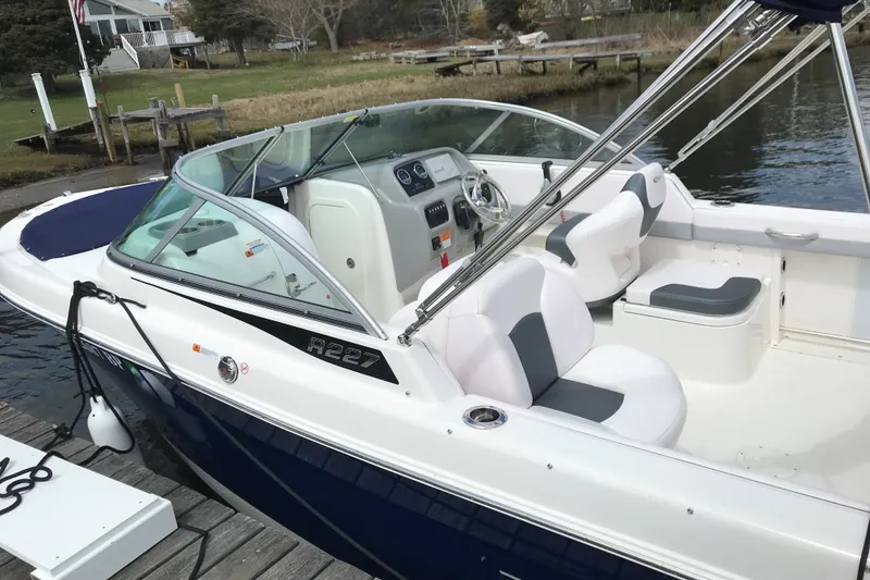 Slide: The Image of 2021 Robalo R227 Dual Console boat docked by a serene waterfront. - 2