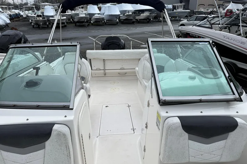 Slide: The Image of 2021 Robalo R227 Dual Console boat interior with open windshield, docked among other boats. - 9