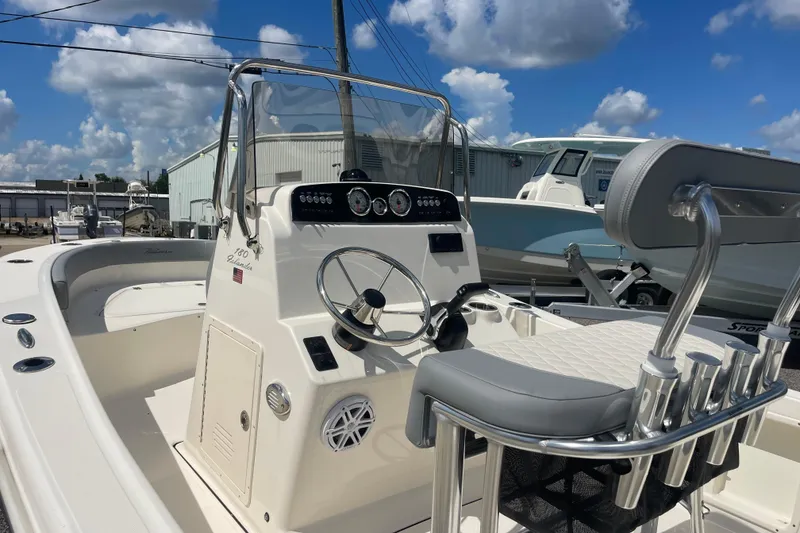 Slide: The Image of 2026 Pioneer 180 Islander boat interior with steering wheel and seating under a blue sky. - 8