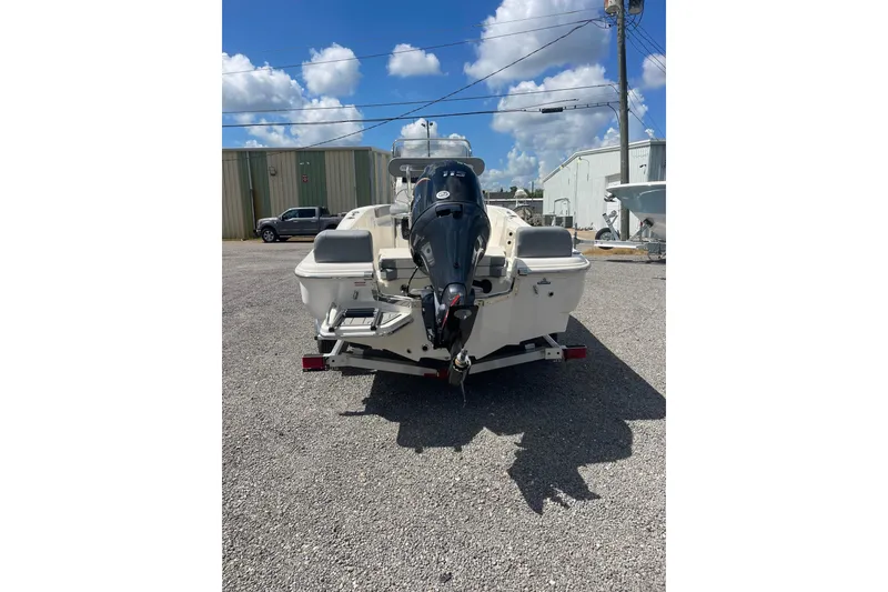 Slide: The Image of 2026 Pioneer 180 Islander boat with outboard motor, parked outdoors under a blue sky. - 2