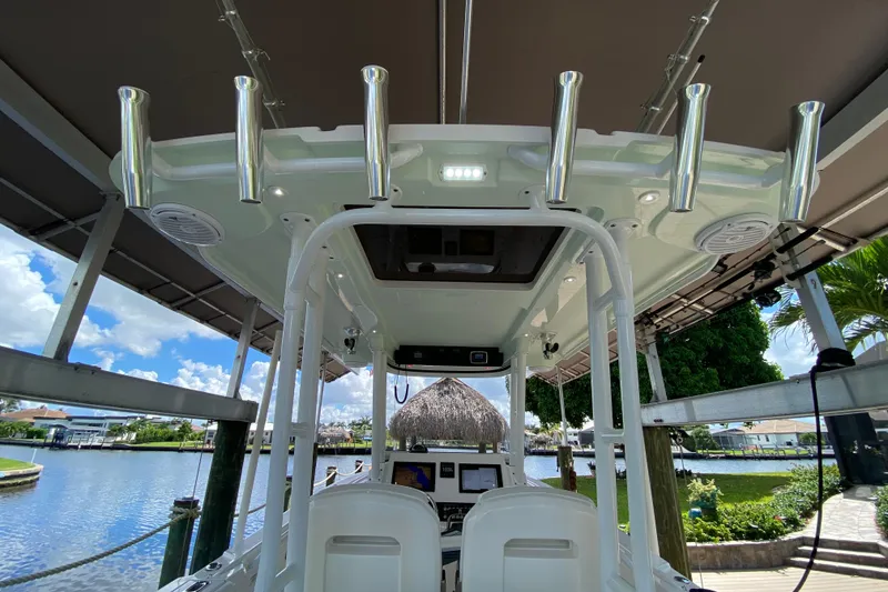 Slide: The Image of 2015 Edgewater 320CC boat interior with rod holders, docked by a scenic waterfront. - 17