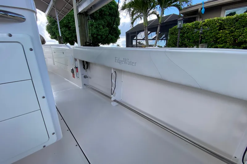 Slide: The Image of 2015 Edgewater 320CC boat interior with white seating and lush greenery background. - 23