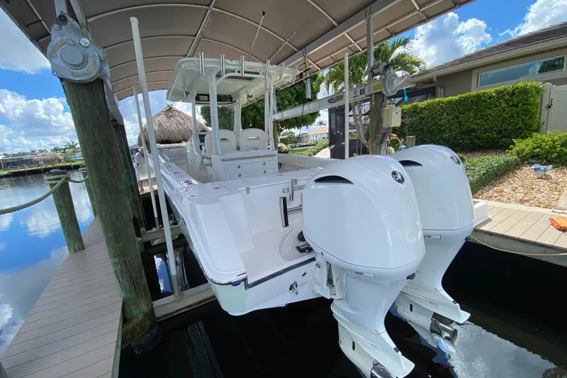 Slide: The Image of 2015 Edgewater 320CC boat with dual engines docked under a canopy. - 5