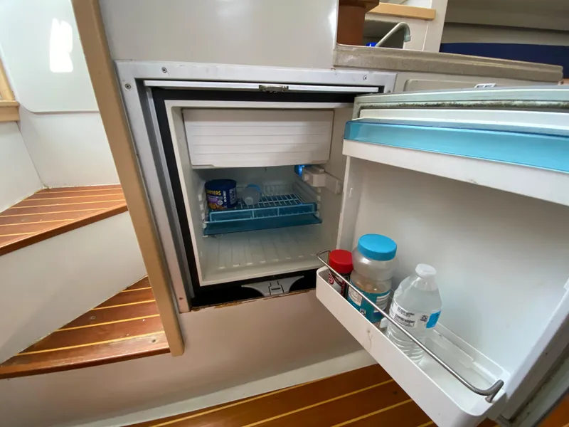 Slide: The Image of Open refrigerator inside a 1997 Stamas 310 Express boat, showing drinks and food storage. - 13