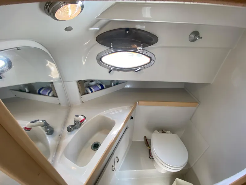 Slide: The Image of 1997 Stamas 310 Express boat bathroom with sink, toilet, and porthole window. - 22